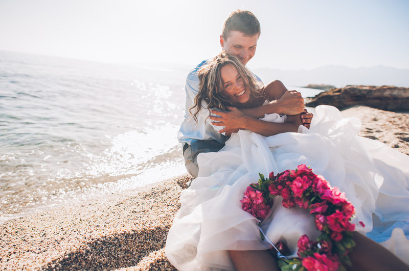 Recently married couple embracing on the beach