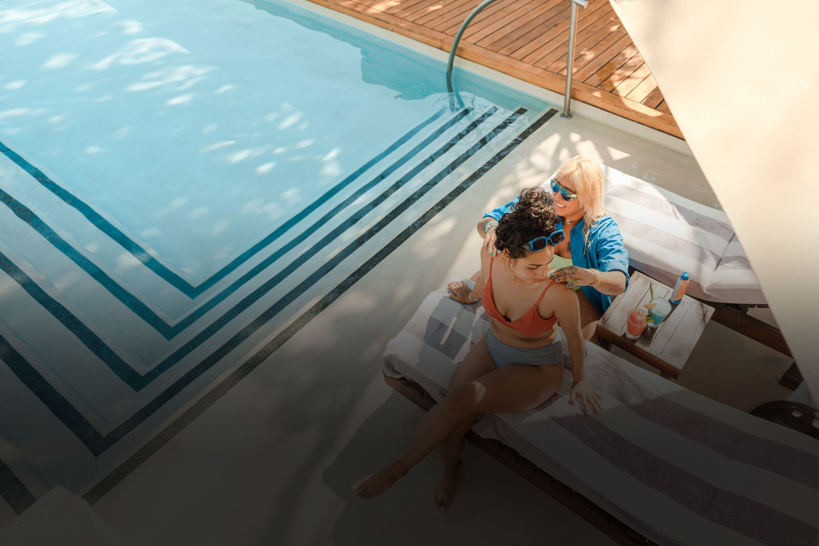 una mujer sentada en una tumbona junto a una piscina